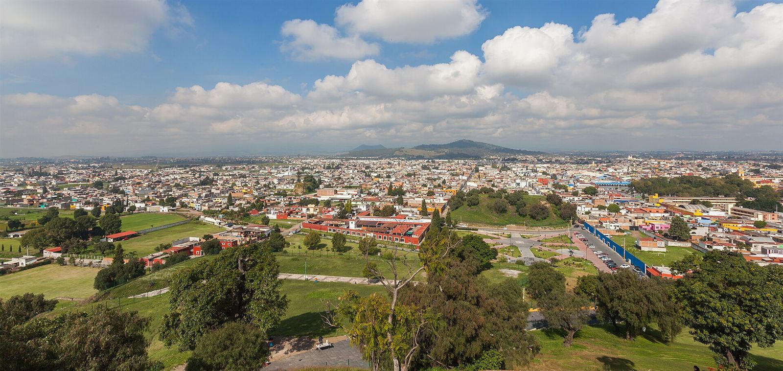 Vista panorámica de Cholula con sus casas, jardines y cerros al fondo